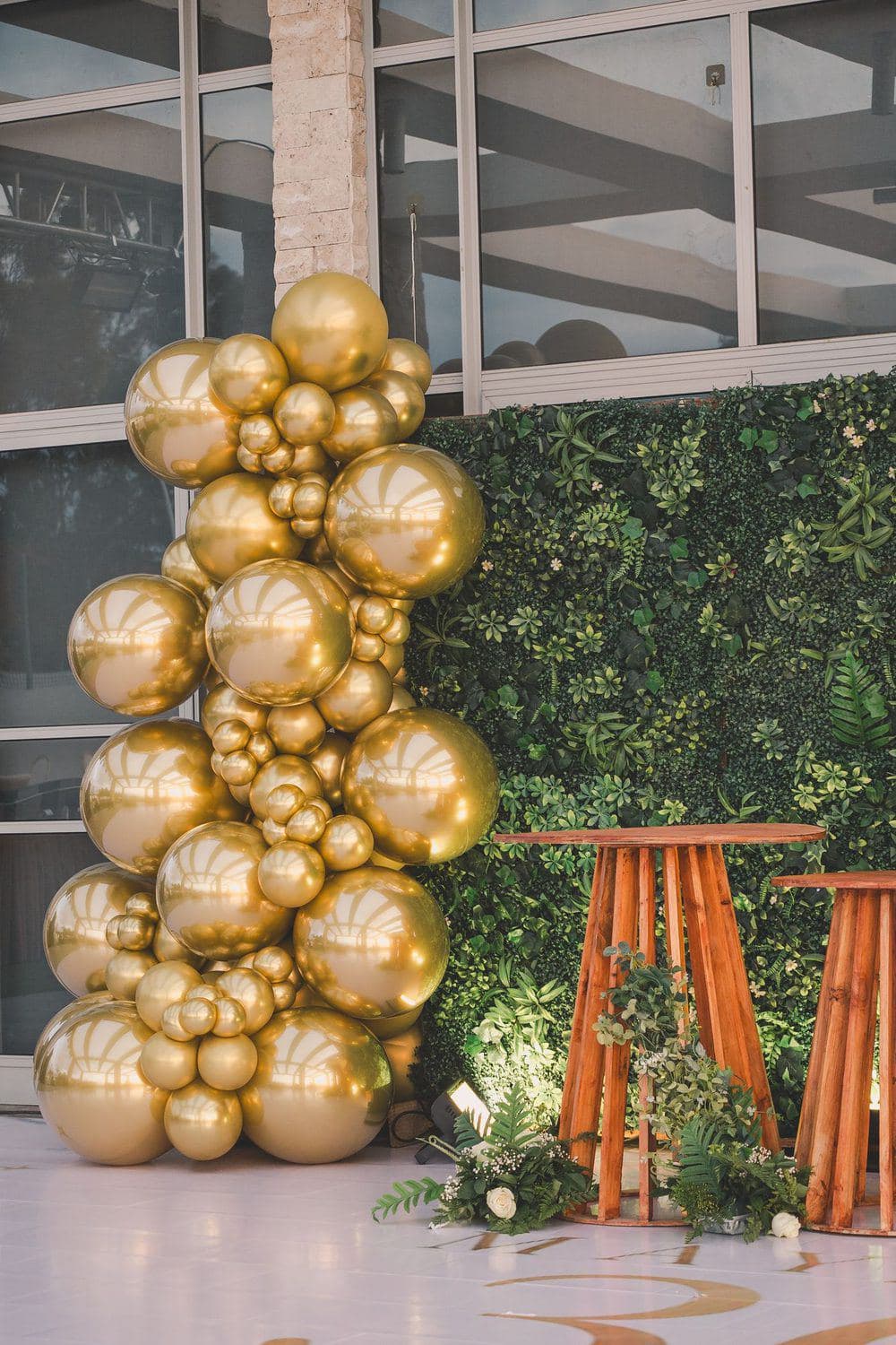 Tall gold balloon column beside a wooden frame in a garden