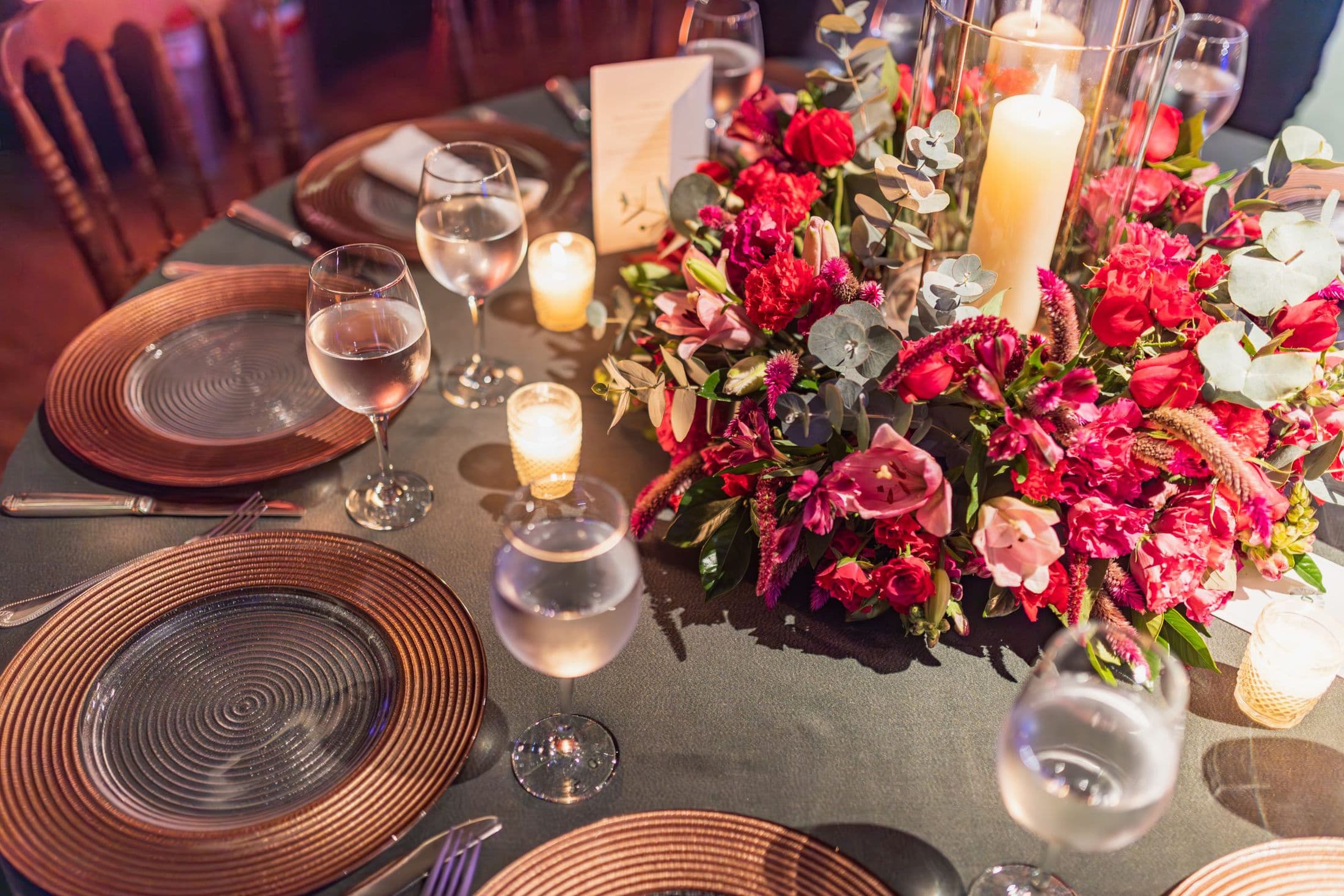 Round table with copper charger plates, red roses and candles